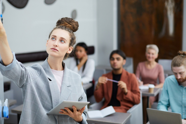 foto di docente alla lavagna e studenti seduti ai tavoli